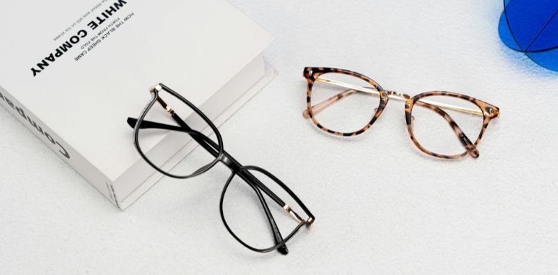 2 Pais of glasses laid on a table with a book